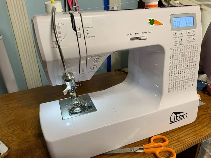 White embroidery machine on top of table next to a pair of scissors