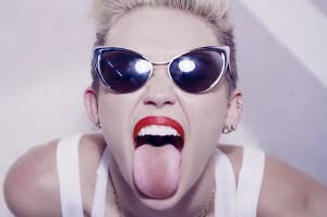 A close up of Miley Cyrus in dark sunglasses with her tongue out