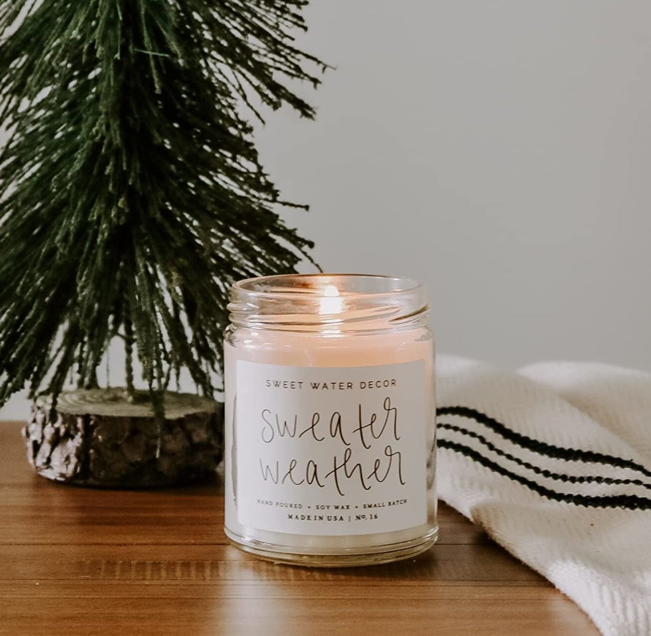 The sweater weather candle next to a mini tree