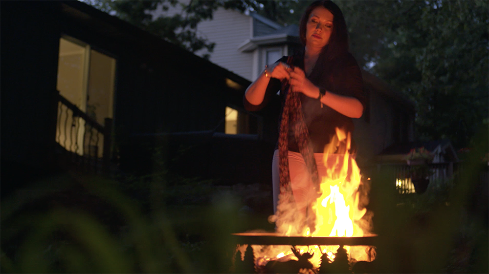 woman frowning and tossing leggings in a fire pit