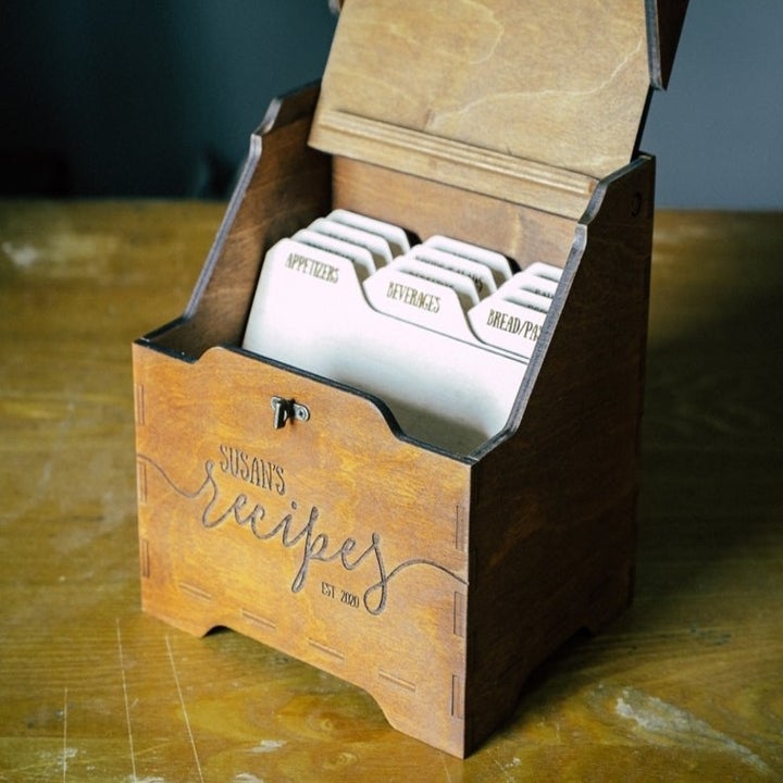 Wooden recipe box with "Susan's recipes est. 2020" engraved and labeled dividers inside