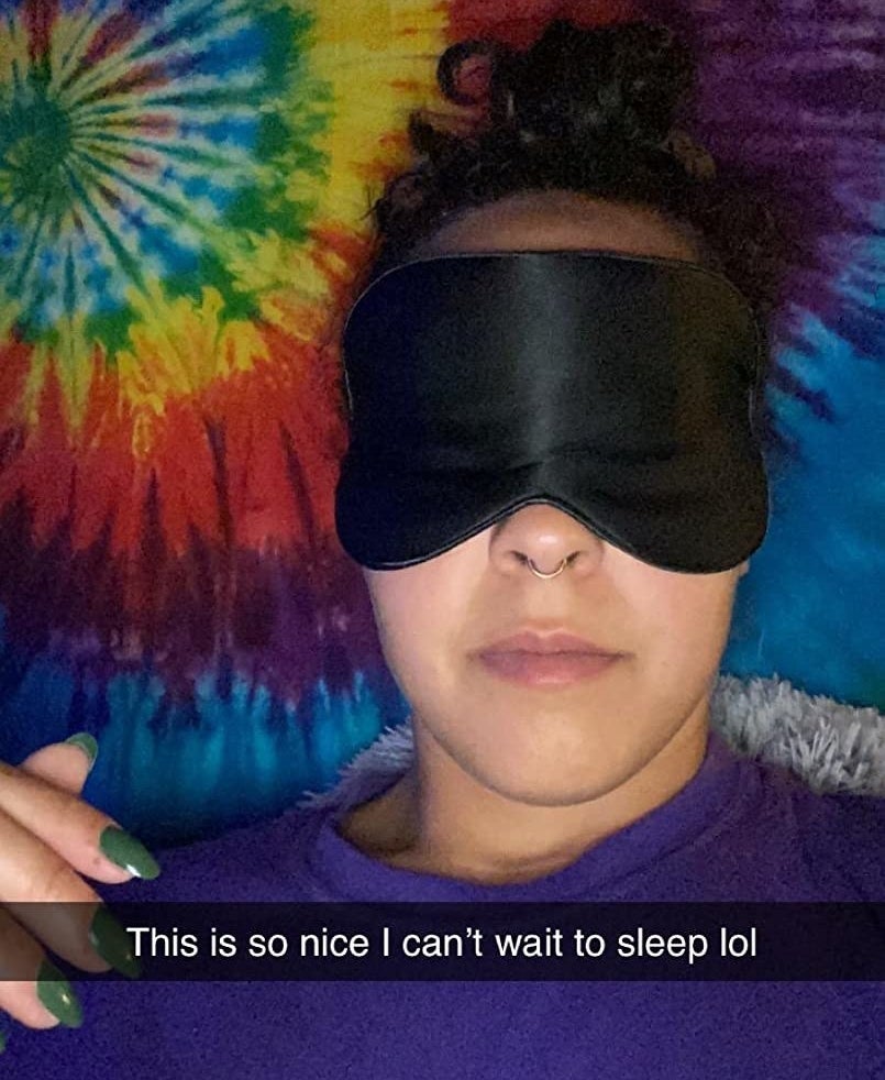 A reviewer wearing the eye mask in black with the SnapChat caption, "This is so nice I can't wait to sleep lol"