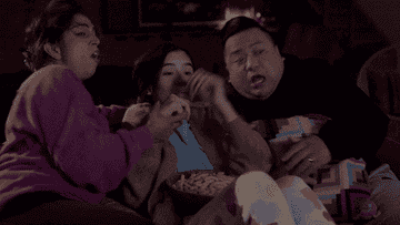 parents and daughter screaming as they watch a horror movie