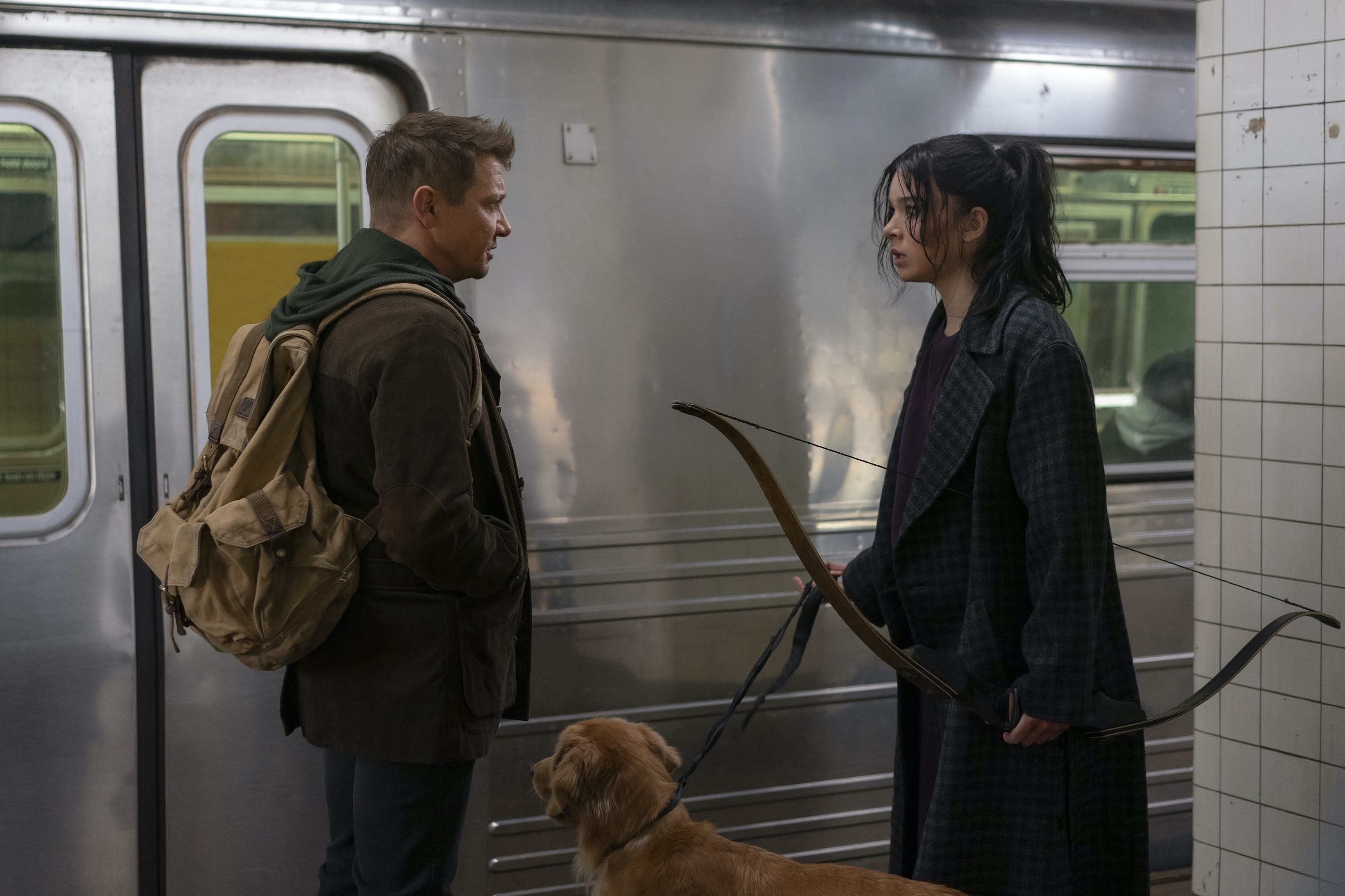 Jeremy Renner and Hailee Steinfeld stand on a subway platform