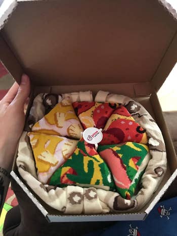 a reviewer holding a pizza container filled with socks that look similar a pizza