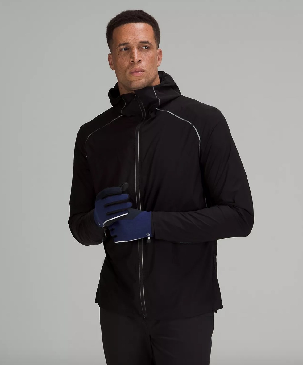 Model wearing navy blue and black gloves with all-black outfit