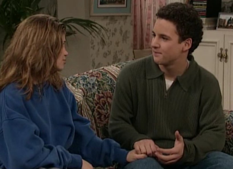 Cory holds Topanga&#x27;s hand and smiles at her as they sit together on a couch