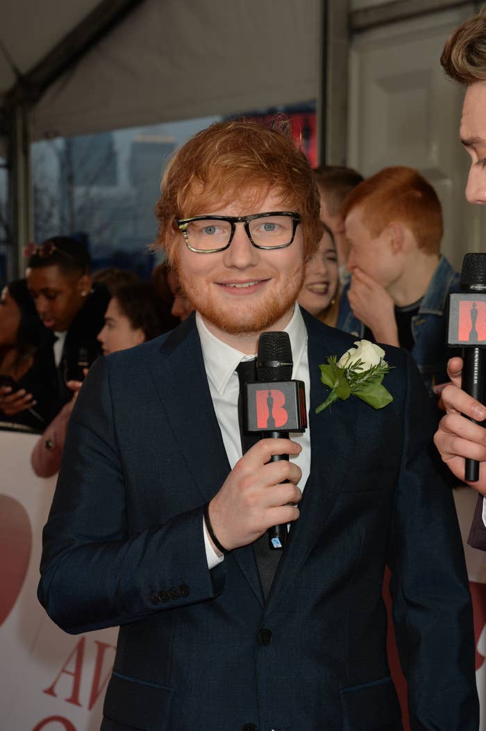 Ed Sheeran looks into a camera while holding a microphone