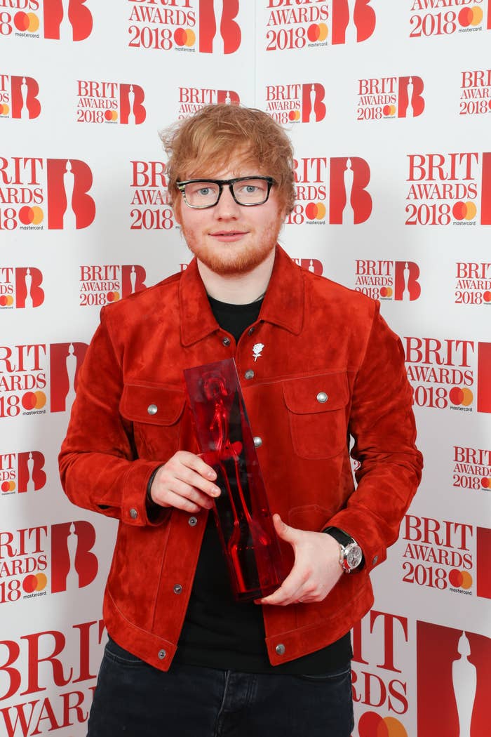 Sheeran holds an award with both hands at a red carpet event