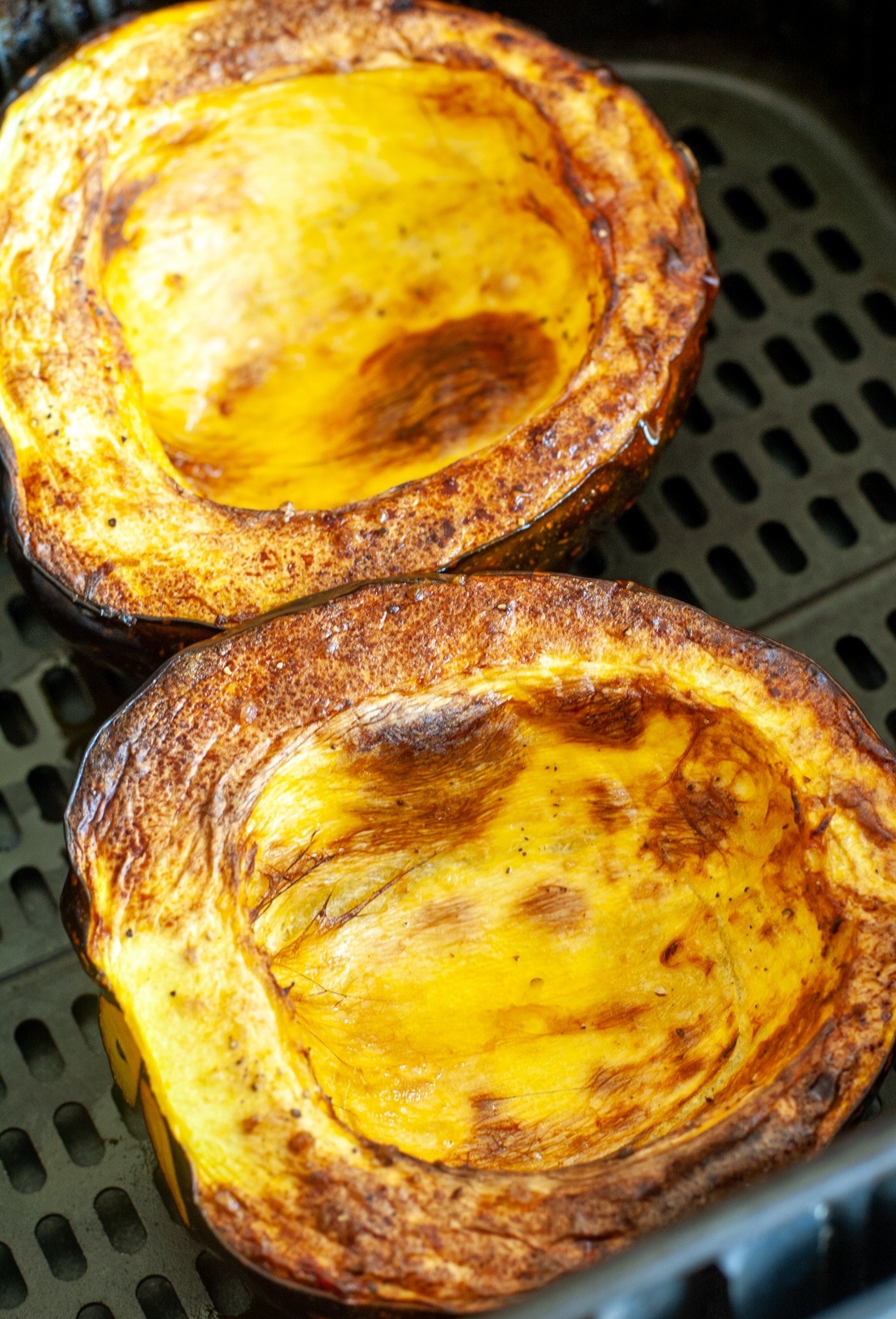 A halved acorn squash in the air fryer.