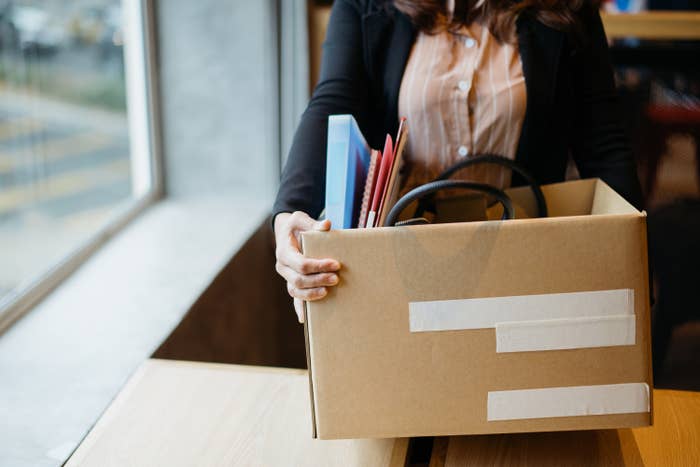 A person carrying a box of items out of their office after quitting their job