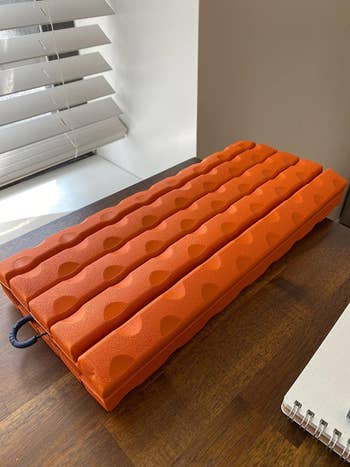 reviewer image of the foam roller in orange, showing how it collapses flat