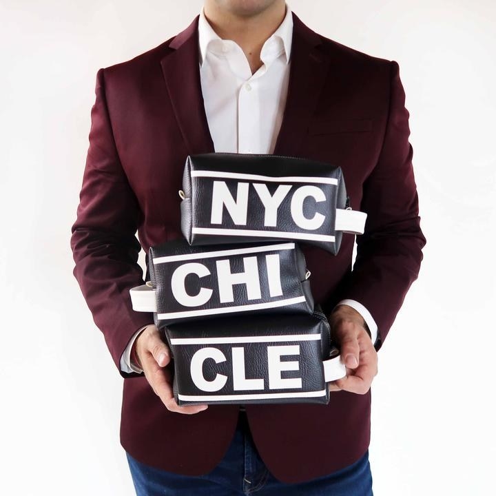 model holding several of the black and white pouches with three-letter city name abbreviations