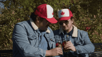 GIF of two men clinking bottles of maple syrup and then drinking them