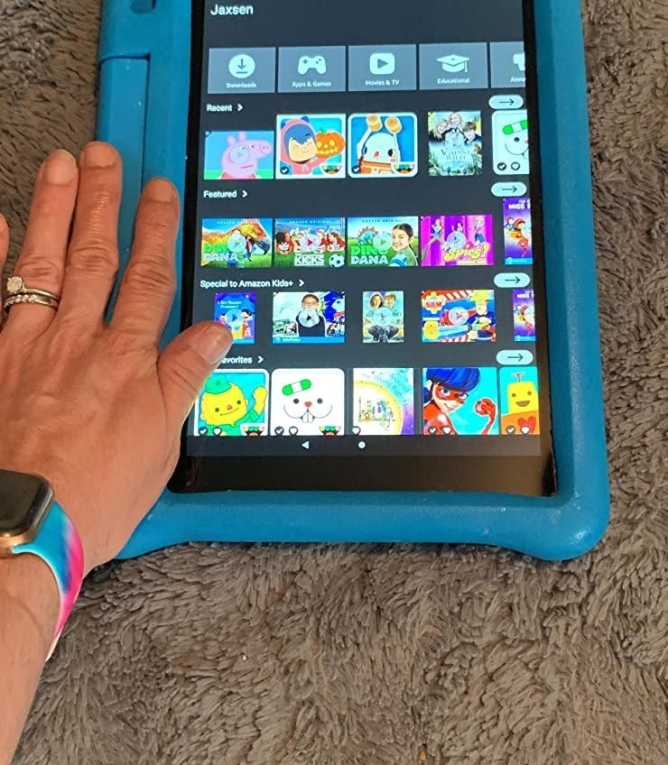 Reviewer holding a blue tablet with apps on display