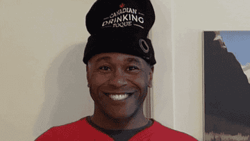 GIF of man dressed in Canadian hockey memorabilia smiling and waving a Canadian flag
