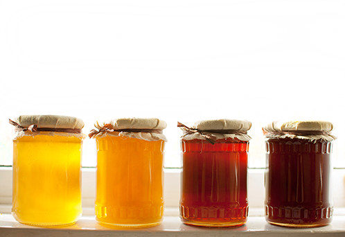 Jars of different colored honey on a counter top