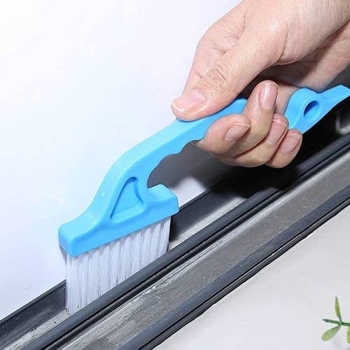 A model using the blue cleaning brush on a window