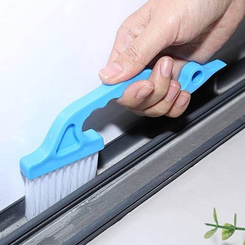 A model using the blue cleaning brush on a window