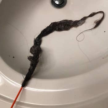 a reviewer photo of the drain snake with the end covered in hair
