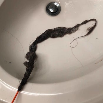 a reviewer photo of the drain snake with the end covered in hair