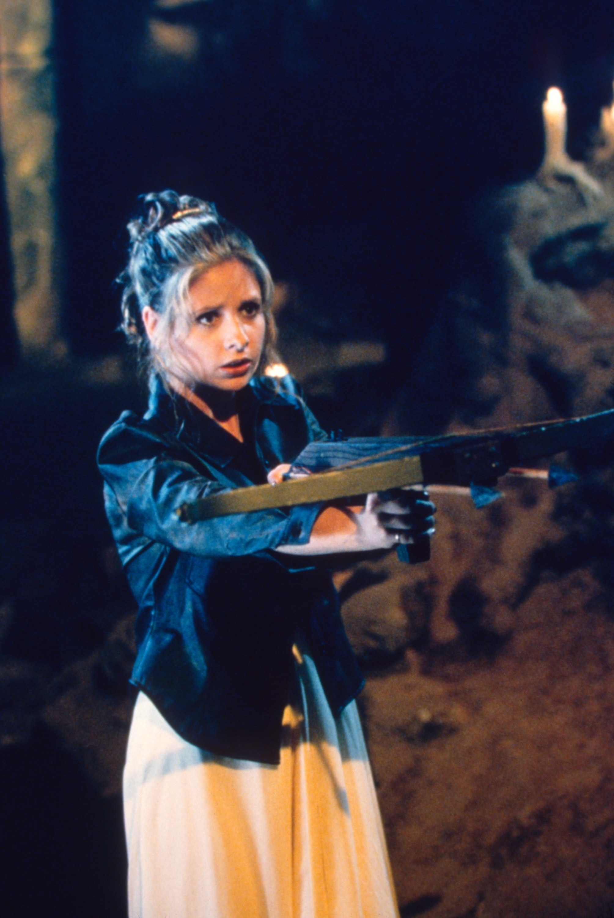 Buffy pointing a crossbow at a vampire while wearing her prom dress
