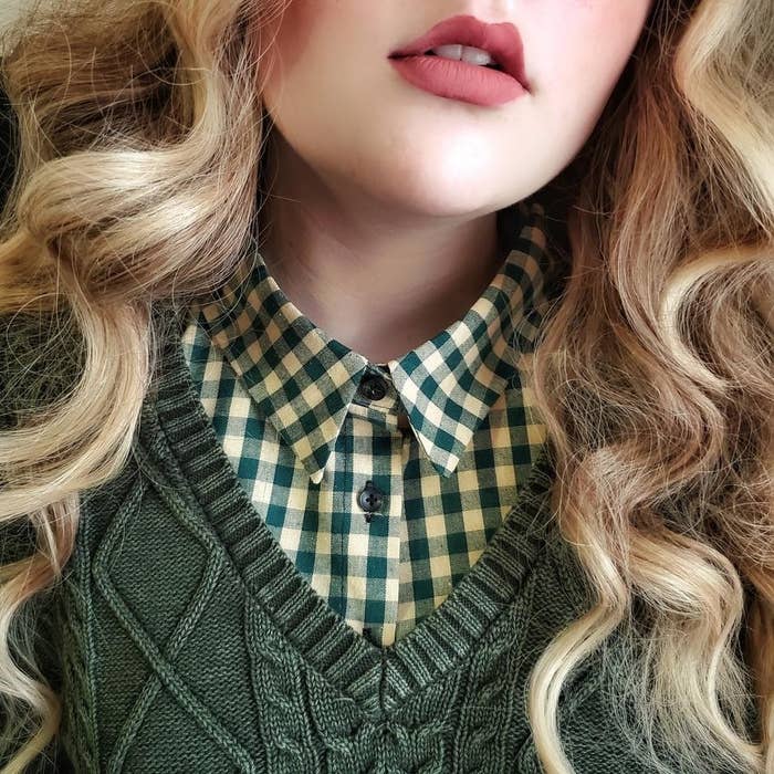 Model is wearing a green gingham collar under a forest green v-neck sweater