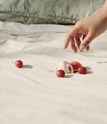 Model reaching for pink egg-shaped vibrator on bed