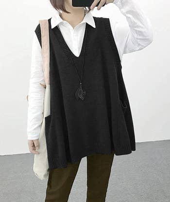 A model wearing the oversized gray sweater vest over a white button down
