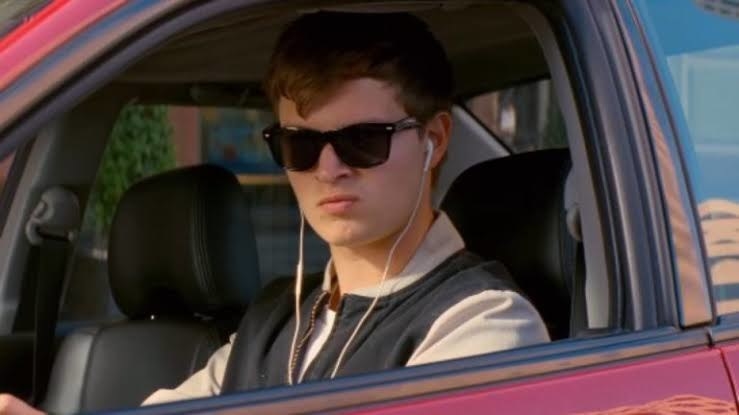 A man looking upset with earbuds in his ears, sitting in his car