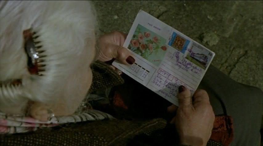 An older woman holding a postcard covered in stamps