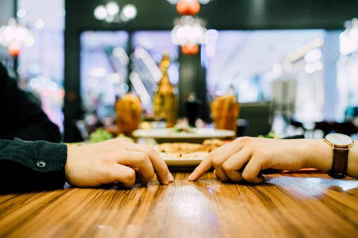 Two people on a date, looking like they want to hold hands, but they don&#x27;t