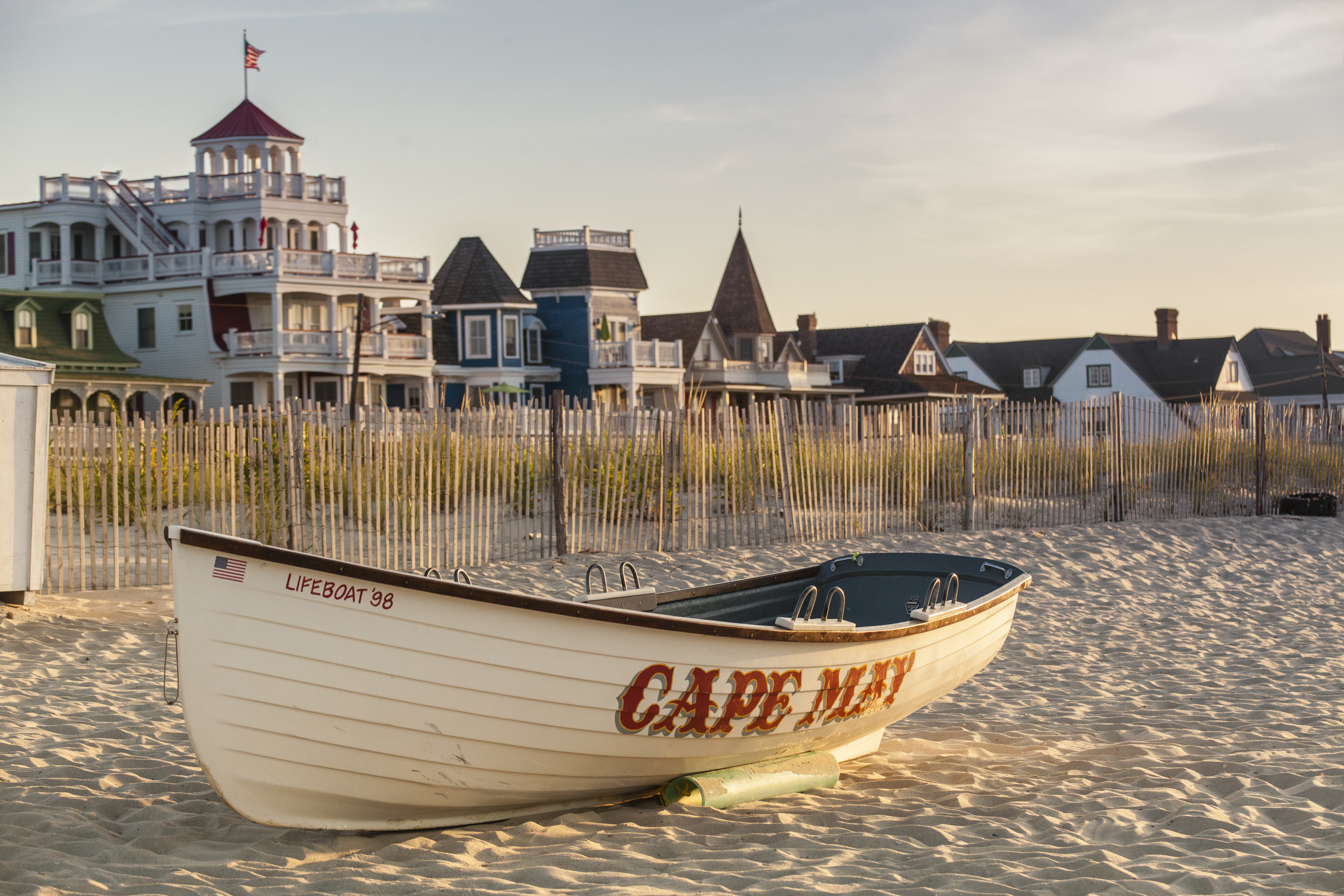 A view of a boat on the beach in Cape May in front of a street of Victorian-style homes