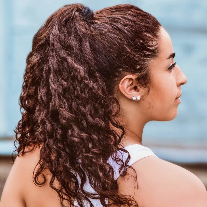 model with long, curly hair wearing hair in a ponytail