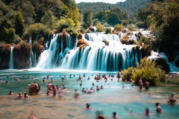 People swimming by waterfall in Krka, Croatia.