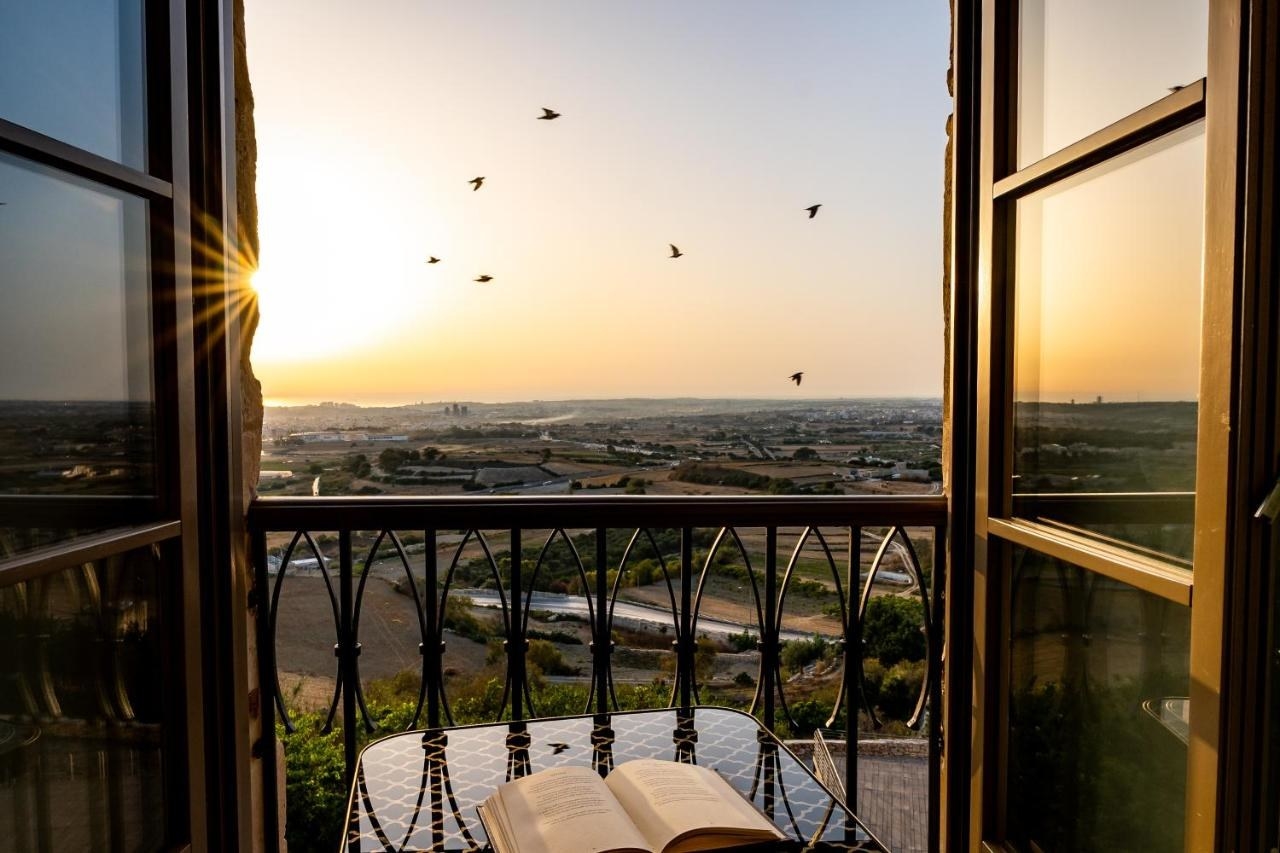 View from the balcony overlooking the Maltese countryside at golden hour, right before sunset. Birds flying in the distance.