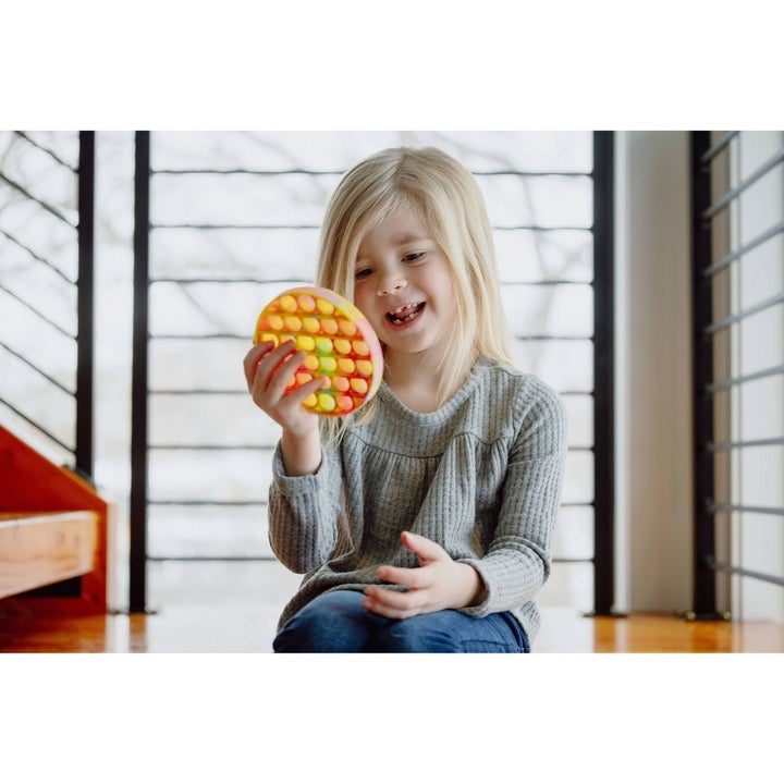 a child holding the rainbow fidget toy