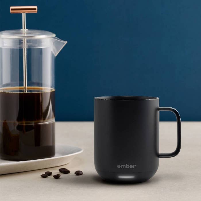 black ember smart mug on a table next to french press coffee