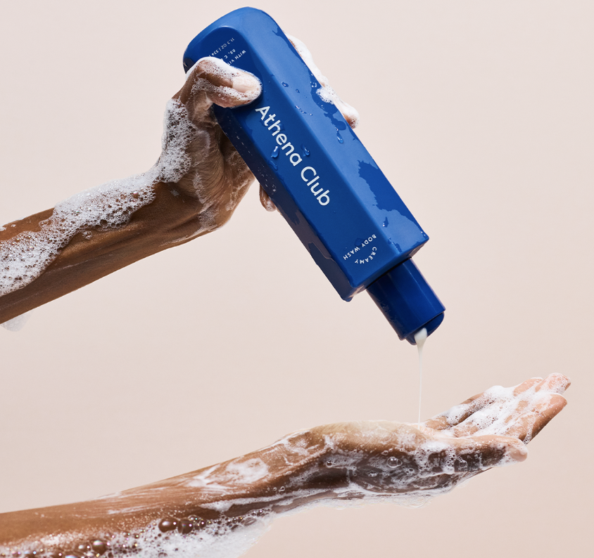 model with sudsy arms pouring body wash into palm of hand