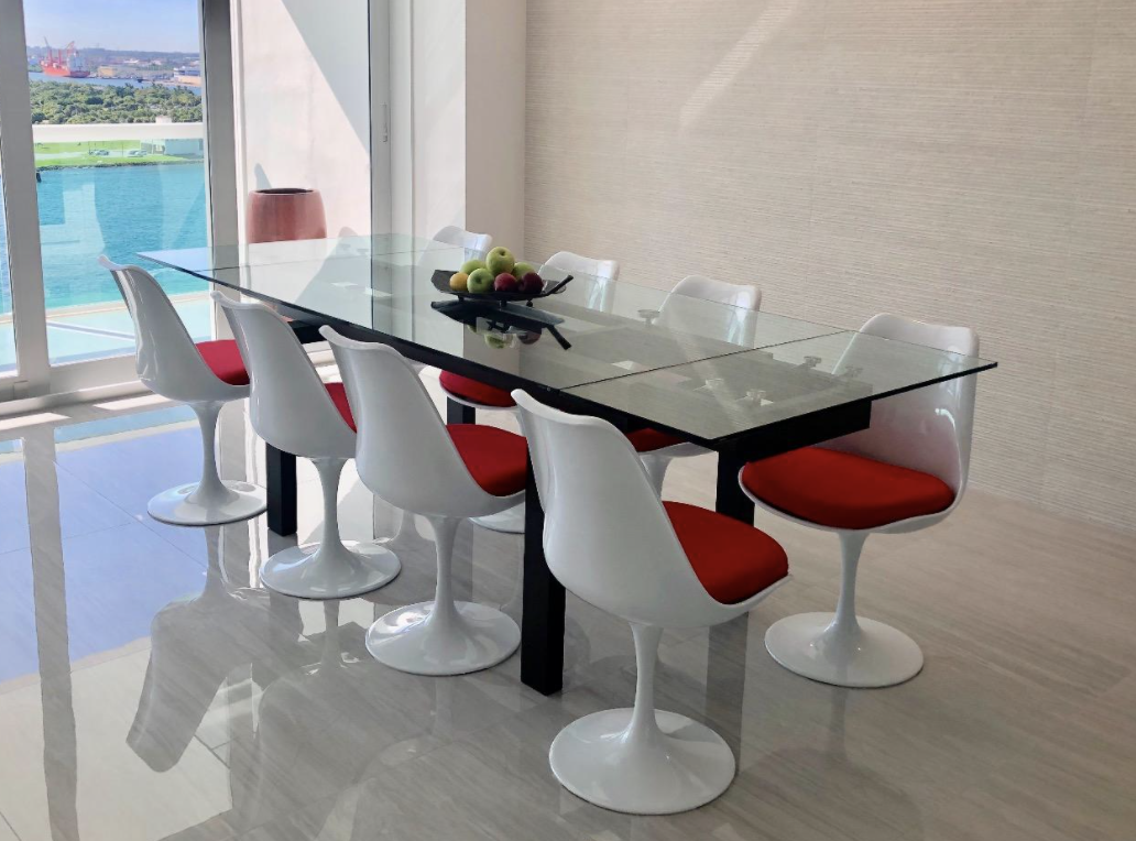 a reviewer photo of the white chairs with red cushions around a glass table