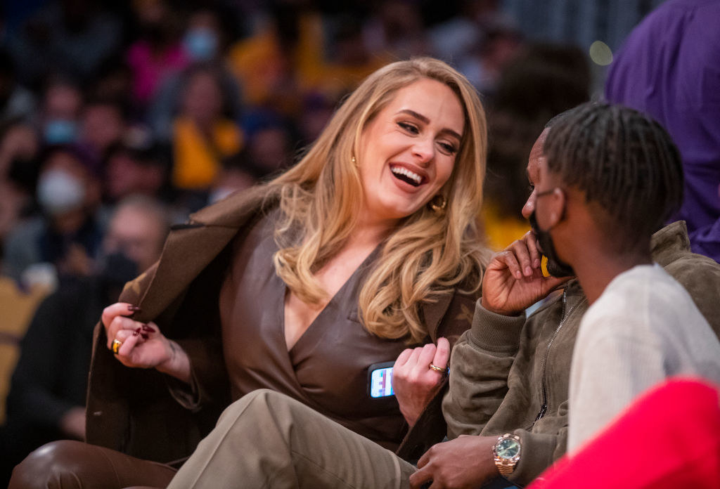 Adele laughs as she sits at a basketball game