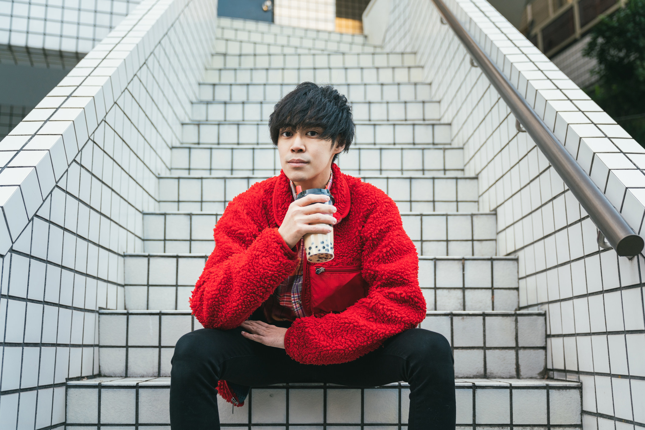 A guy sitting on steps and drinking boba tea