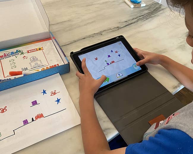 a child's drawing and them playing a game of their drawing on an iPad