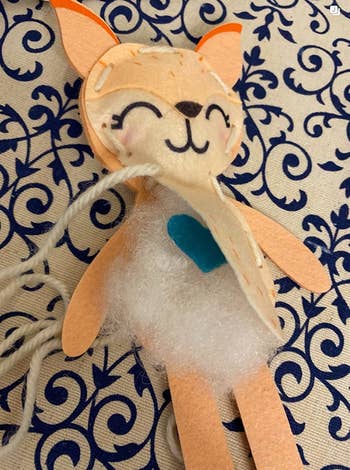 a felt fox half sewed closed to show its blue felt heart and stuffing