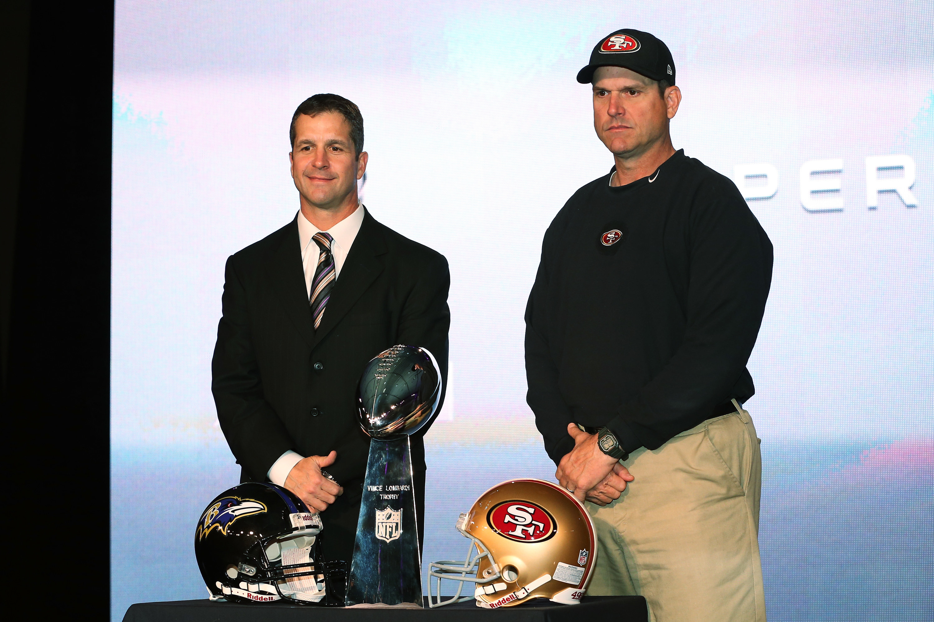 Harbaugh brothers stand with the Super Bowl trophy