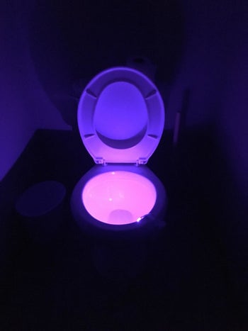 reviewer's photo showing their toilet glowing with a purple light