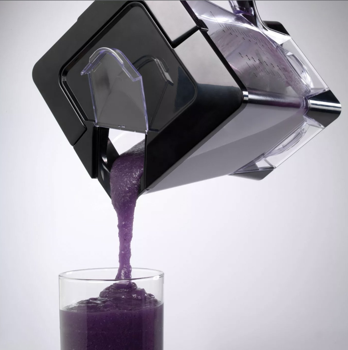 The blender pouring a purple smoothie into a glass