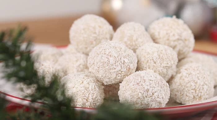 A photo of white chocolate snowball truffles stacked on a plate