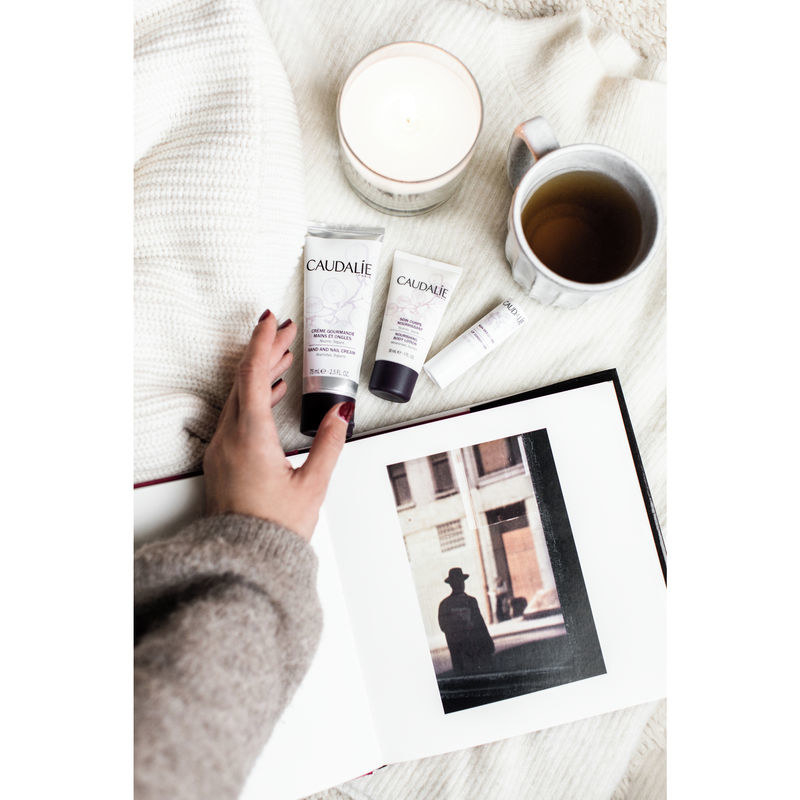 A hand reaching for the tube of Caudalie cream