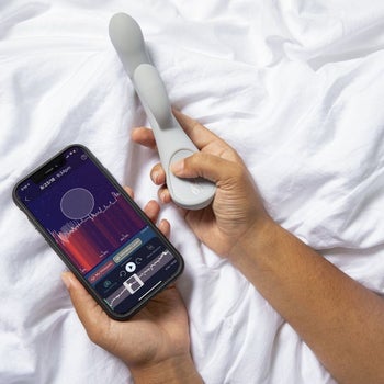Model holding gray rabbit vibrator and cell phone with compatible smart app